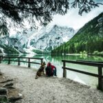 Active man and dog looking at Pragser Wildsee or Braies Lake
